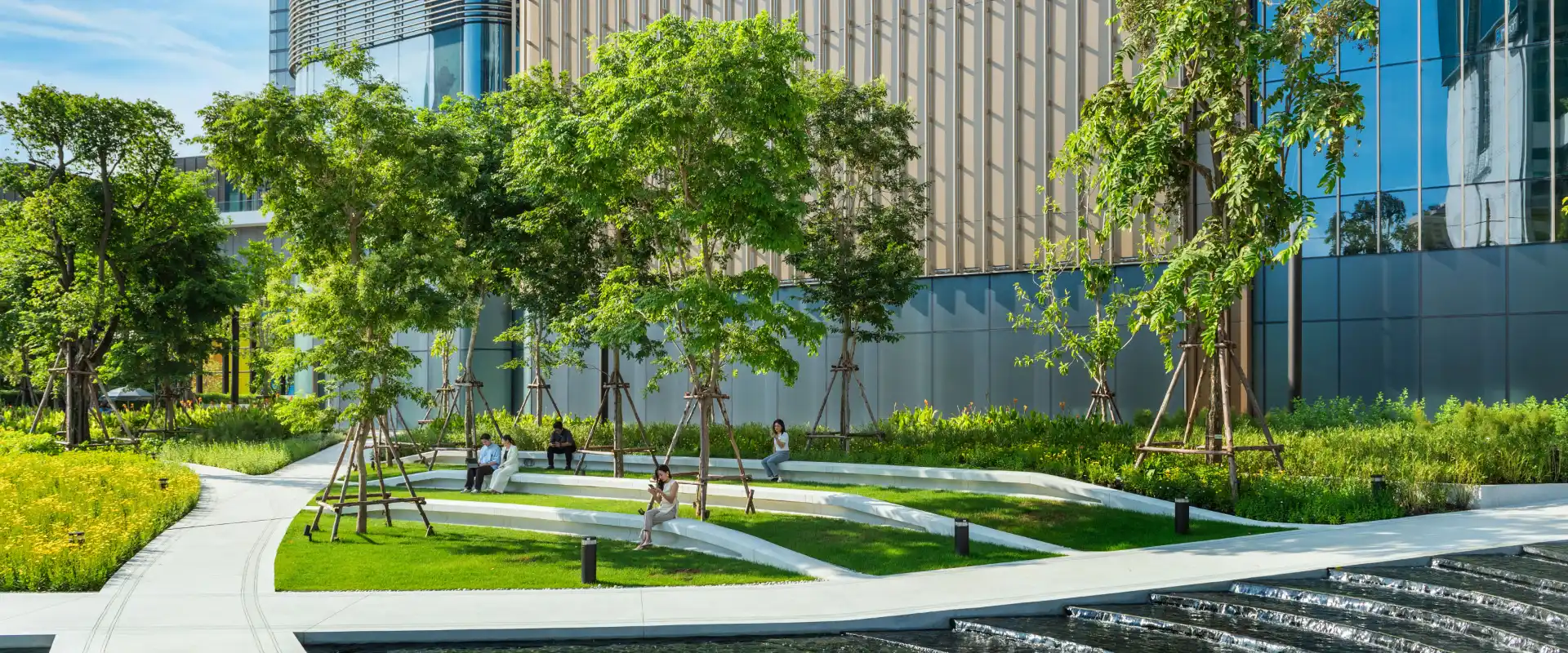 Terraced lawns, trees, seating and a water feature in One Bangkok Park, Lumphini, Bangkok.