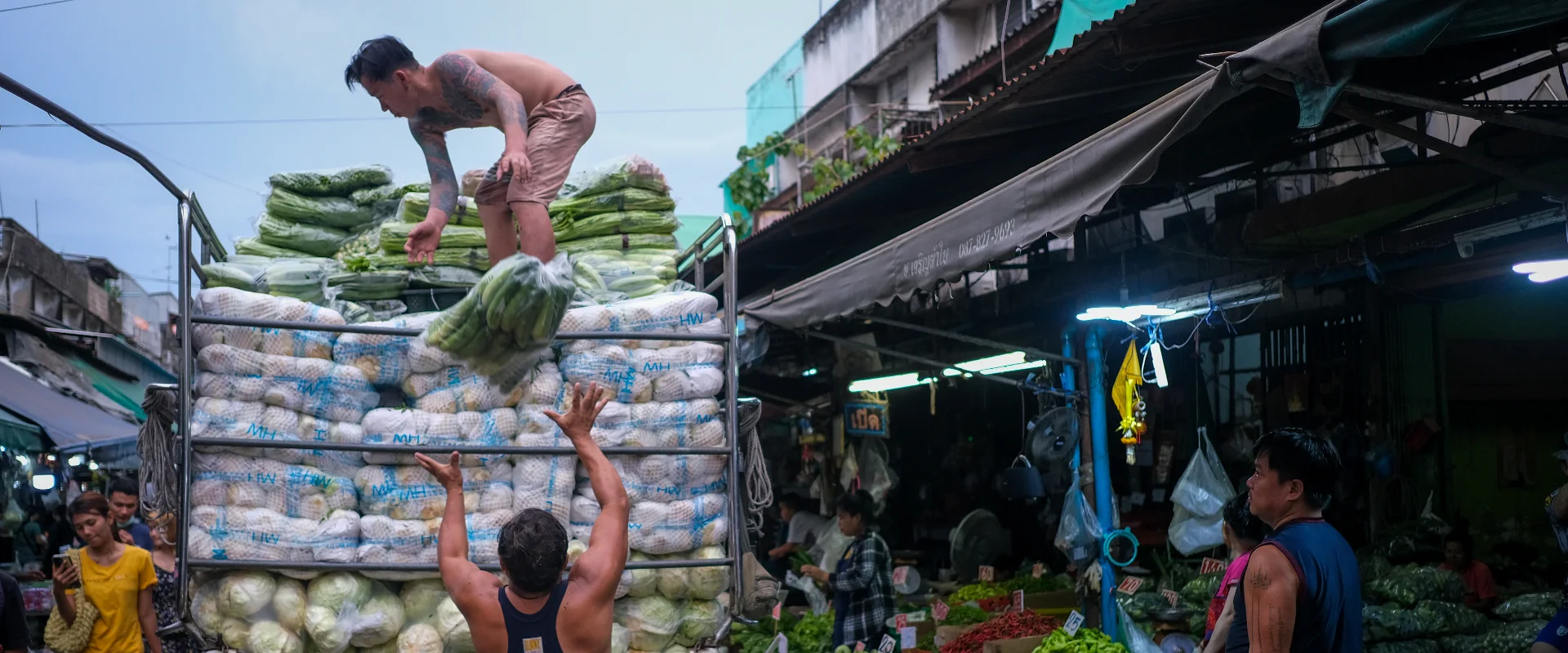 Workers unload fresh produce from a pickup at Khlong Toei Market, Bangkok.