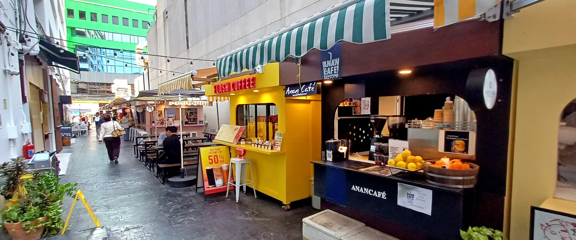 The paved Ari Alley shopping passage, with separate café counters, striped awnings and tables