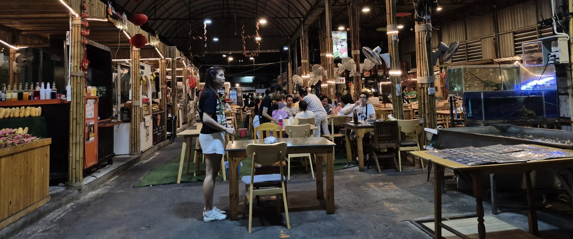 Food stalls and shared dining tables beneath the covered roof at At One Market, Sukhumvit Soi 1