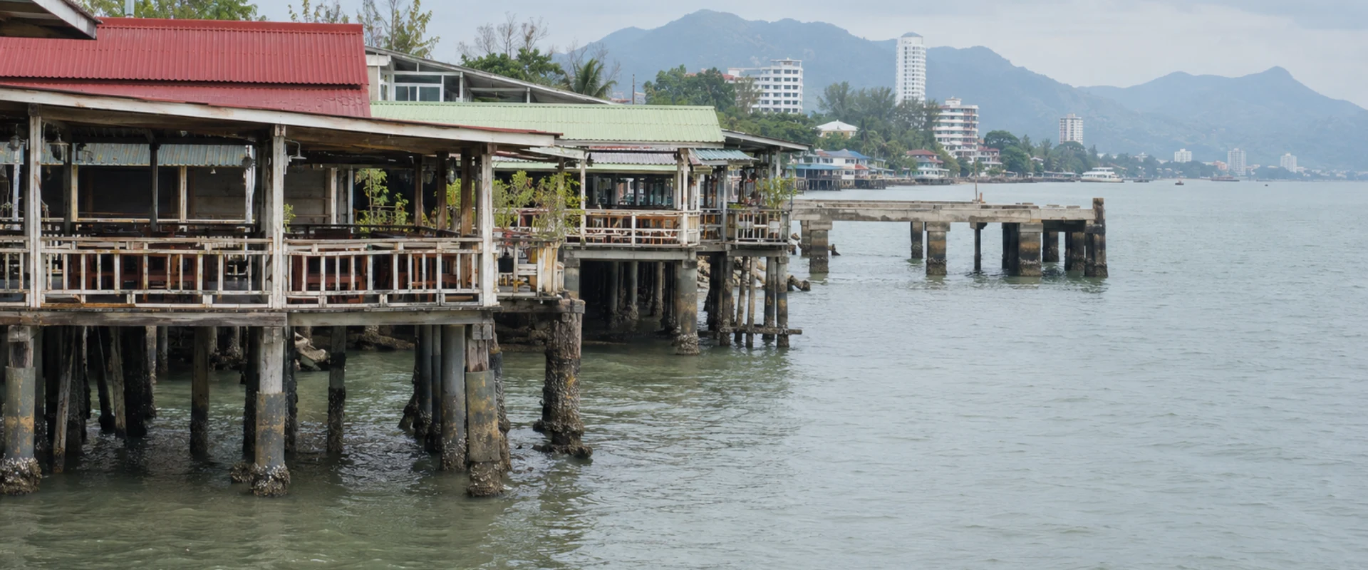 AI-generated photographic-style image of generic waterfront buildings on stilts beside the sea.